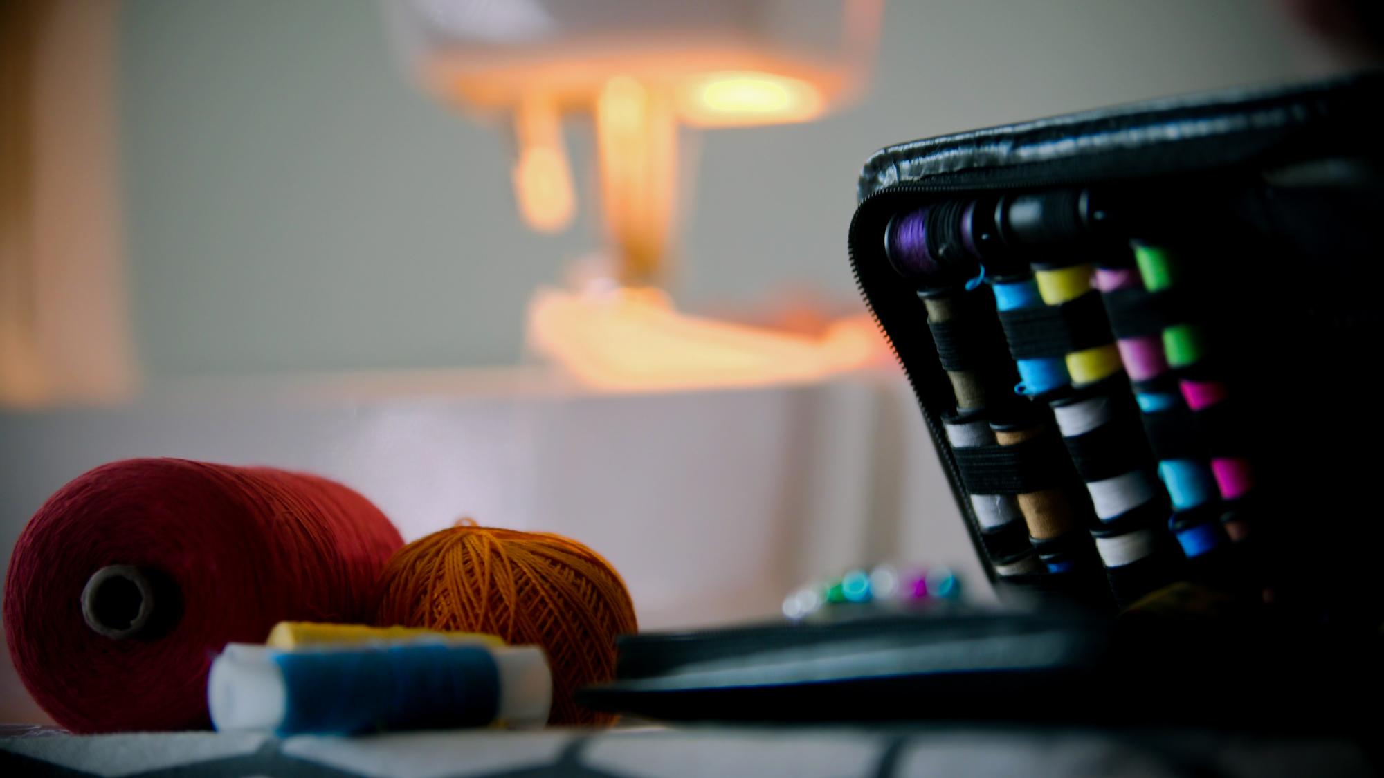 Workshop bench with threads and a digital embroidery pattern on screen
